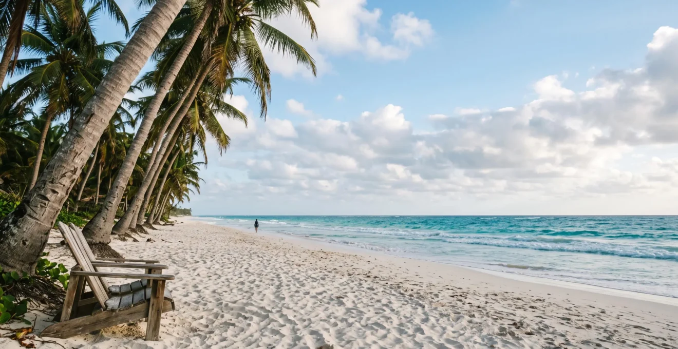Rangée de cocotiers penchés sur une plage de sable blanc face à une mer turquoise, image emblématique de carte postale tropicale