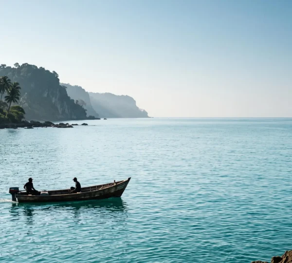 Petit bateau en bois voguant seul sur une mer turquoise calme au large d'une côte sauvage des Caraïbes, sans autre embarcation à l'horizon