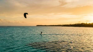 Silhouette d'un pratiquant de sport nautique glissant sur une eau turquoise des Caraibes au coucher du soleil