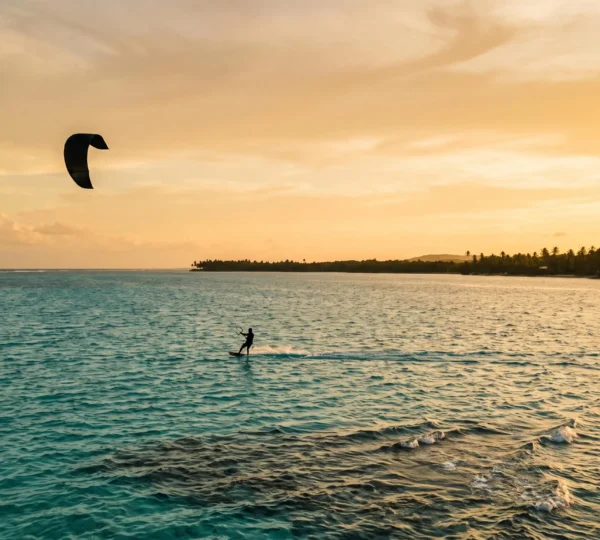 Silhouette d'un pratiquant de sport nautique glissant sur une eau turquoise des Caraibes au coucher du soleil